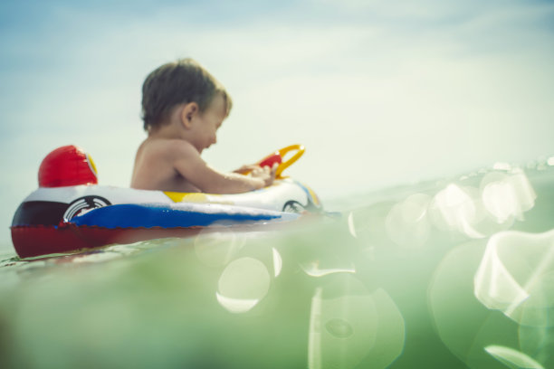 小男孩坐在充气木筏上，在海上享受海滩假日图片下载