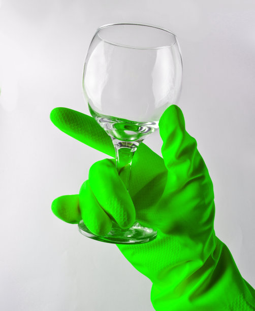一个戴着绿色乳胶手套的男人的手拿着一个干净的酒杯图片下载