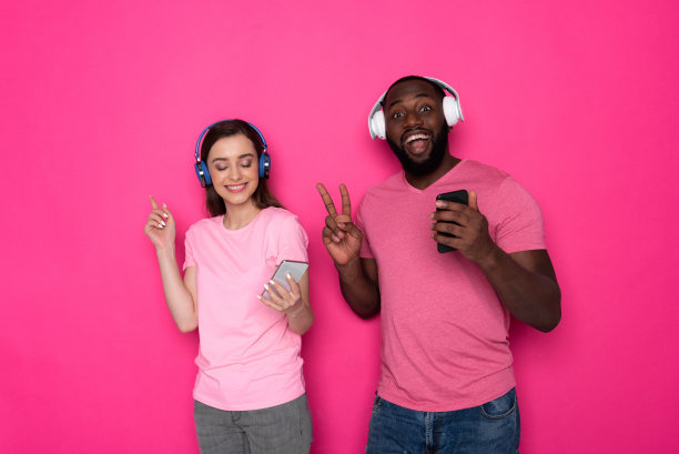 半长时尚的跨种族夫妇戴着现代耳机在工作室图片下载