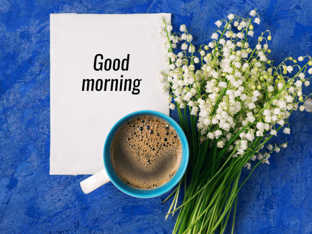 一杯咖啡和一束铃兰在蓝色背景上写着早上好图片下载