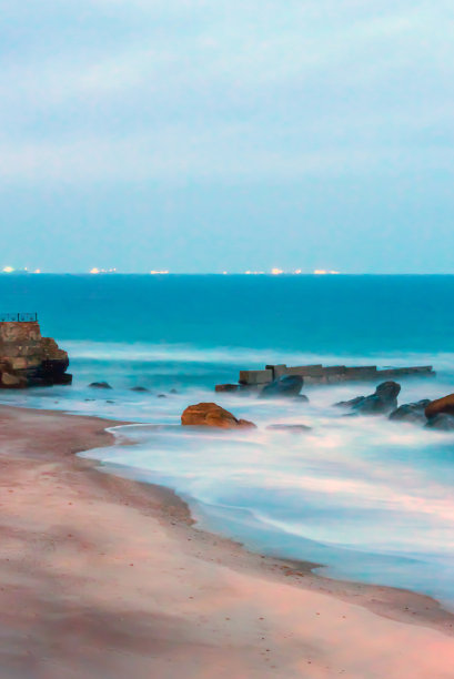 使用长时间曝光的傍晚海滨的照片。在地平线上你可以看到城市的灯光。图片下载