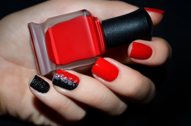 有红色指甲设计的女性手握指甲油瓶。图片下载