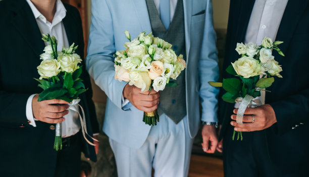 淡蓝色西装的新郎捧着婚礼花束。伴郎朋友就站在旁边。优雅的照片。图片下载