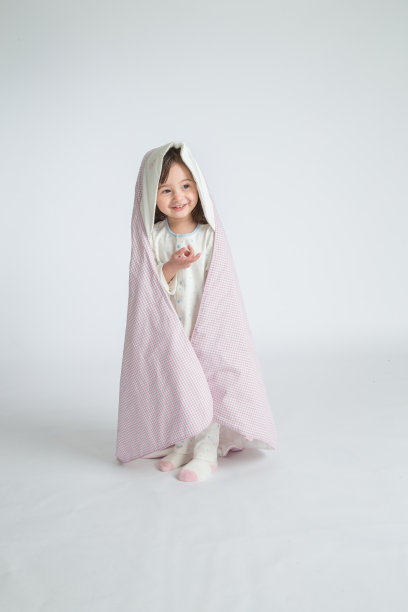 一个小女孩抱着一个婴儿，孩子站在地板上。水平的照片。浅灰色背景图片下载