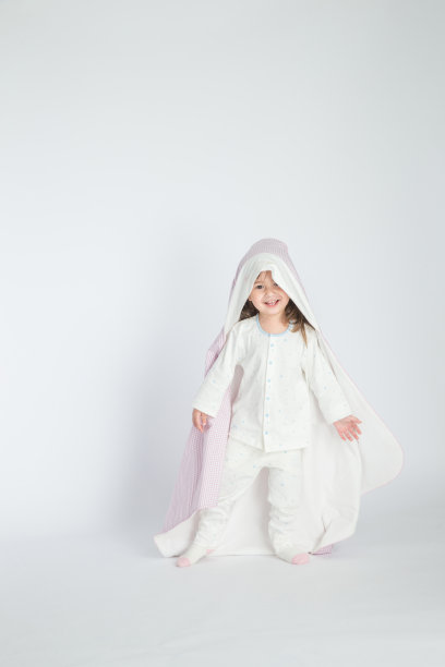 一个小女孩抱着一个婴儿，孩子站在地板上。水平的照片。浅灰色背景图片下载