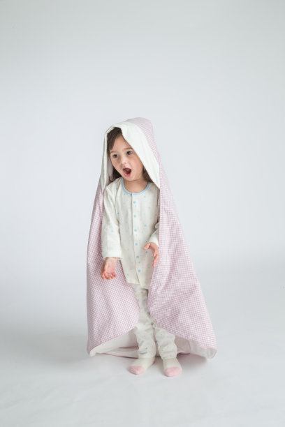 一个小女孩抱着一个婴儿，孩子站在地板上。水平的照片。浅灰色背景图片下载