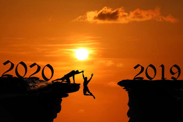 2020年新年的剪影概念，在红色的天空日落时，人在洞穴或高悬崖上跳跃和攀登图片下载