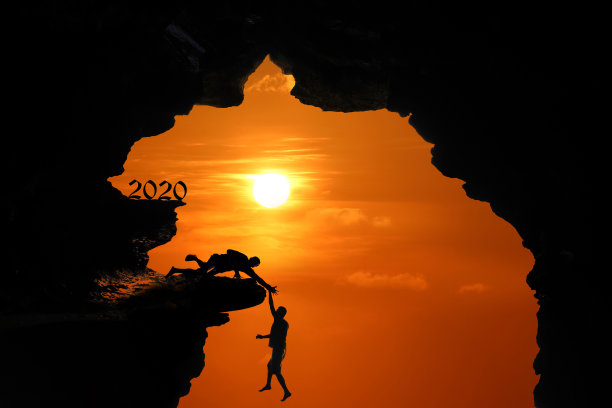 2020年新年的剪影概念，在红色的天空日落时，人在洞穴或高悬崖上跳跃和攀登图片下载