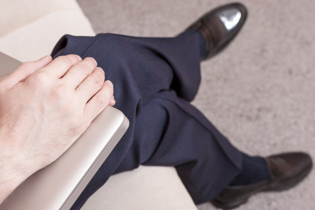 白人男性的手拿着笔记本电脑。坐在室内沙发上。专注于手中。图片下载