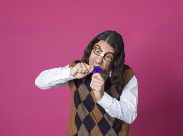 书呆子拿着避孕套，粉红色的背景图片下载