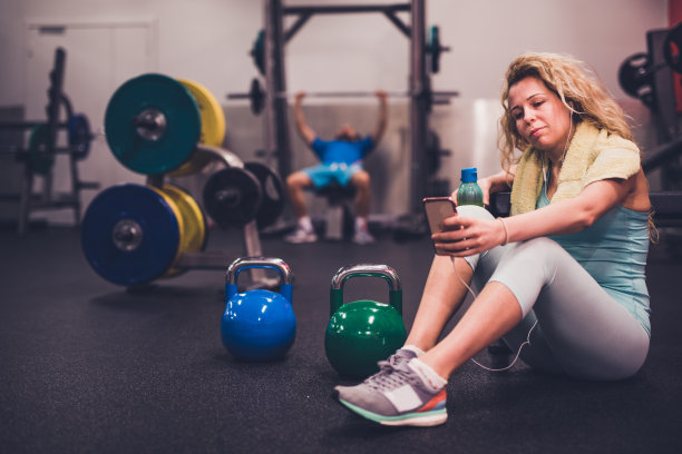 金发女郎一边听音乐，一边在健身房里休息。图片下载