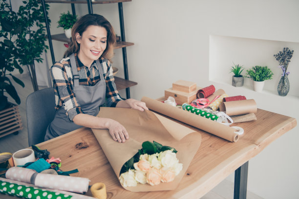 特写照片美丽，细心，她，她的夫人在准备白玫瑰束礼物礼物纸，零售商助理，组成diy鲜花开放业主小家庭花店室内房间图片下载
