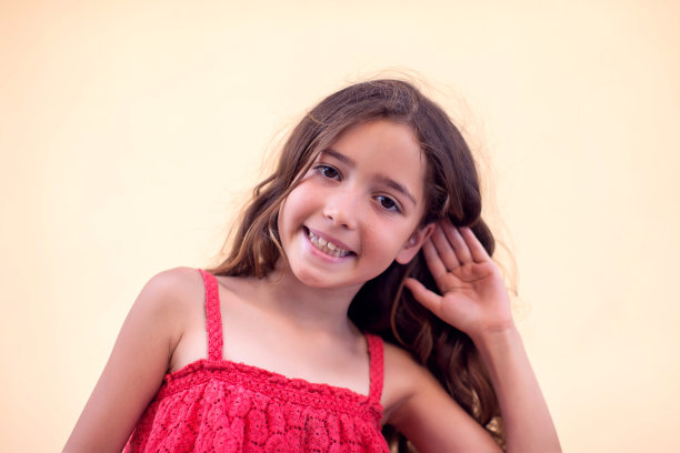 小女孩把手放在耳边微笑着。儿童与情绪概念图片下载