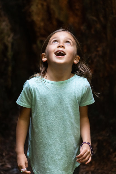 一个小女孩在树林里抬头看图片下载