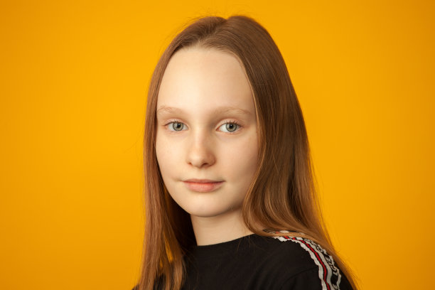 在黄色背景上的黑色t恤少女的工作室肖像图片下载