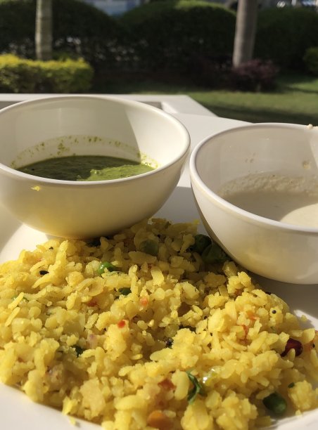 这是印度早餐poha的图片，用水煮米饭和洋葱做成，上面有烤花生，还有薄荷酸辣酱，这是印度酒店餐厅自助早餐的一部分，不健康的早餐照片，在印度马哈拉施特拉邦很流行，图片下载