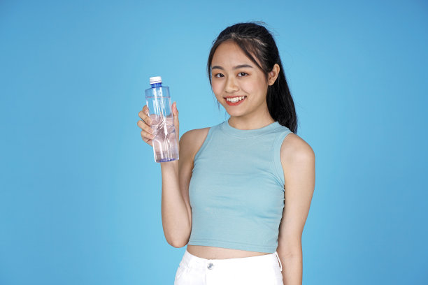 亚洲年轻貌美的年轻女学生与空白瓶纯瓶在蓝色背景图片下载