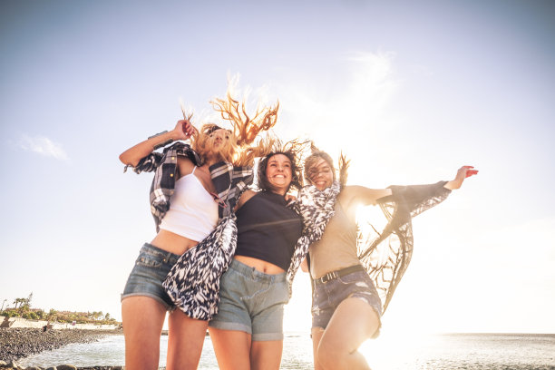 年轻人在一起玩得很开心——年轻的朋友们，美丽的高加索女孩，穿着夏天的衣服，在沙滩上玩着，笑着，享受着夏天的假期图片下载