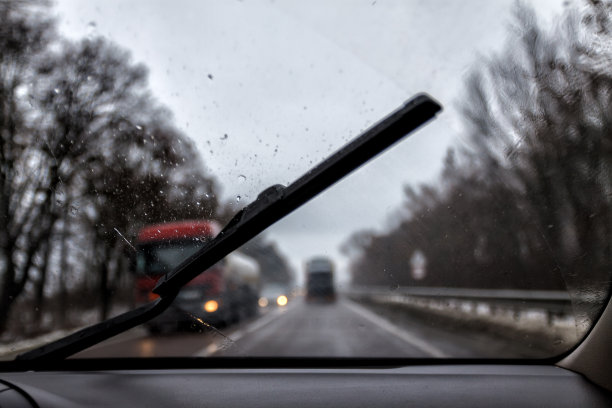 照片透过挡风玻璃的汽车在雨夜，在模糊的灯光，轨道，卡车图片下载