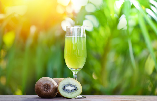 玻璃杯猕猴桃汁和切片猕猴桃与自然绿色的夏季背景图片下载