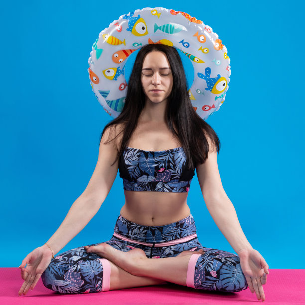 女孩坐在一个粉色的健身垫上沉思，梦想着一个假期，头上戴着一个圆圈，关于夏天、假期和生活方式的概念图片下载