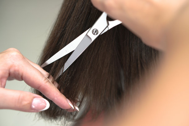 理发师理发的过程。沙龙里的女人捋着头发。用剪刀手。设计图片图片下载