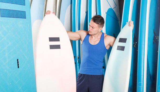 一个年轻人在冲浪俱乐部找冲浪板图片下载