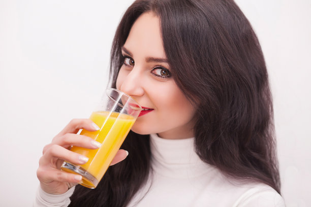 快乐微笑的年轻女子喝着橙汁图片下载