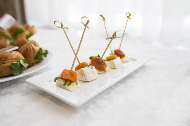 自助餐菜。白盘子上的开胃小菜。小三明治串在棍子上。零食图片下载