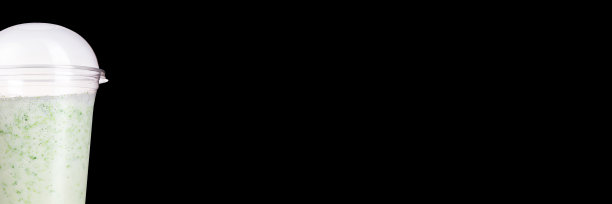 美味的水果鸡尾酒在一个塑料杯，在一个黑色的背景。奶昔横幅。图片下载
