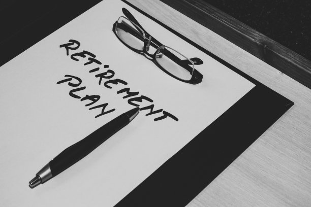 黑白照片，老花镜和钢笔坐在一张纸上写着退休计划的信息图片下载