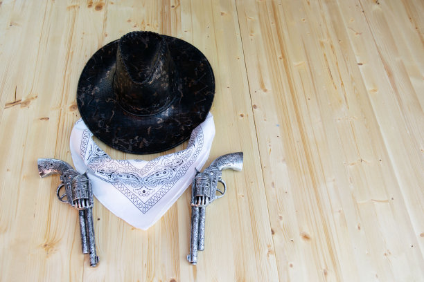 木制背景上的牛仔配件(帽子、围巾和两把枪)图片下载