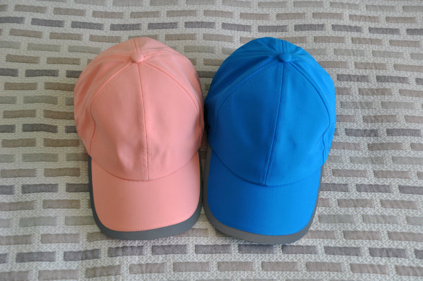 粉色和蓝色棒球帽在印花织物背景。空间的文本。图片下载