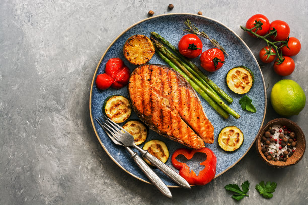 烤鲑鱼配蔬菜西葫芦，芦笋，番茄，甜椒，灰色背景。俯视图，平放，复制空间。图片下载