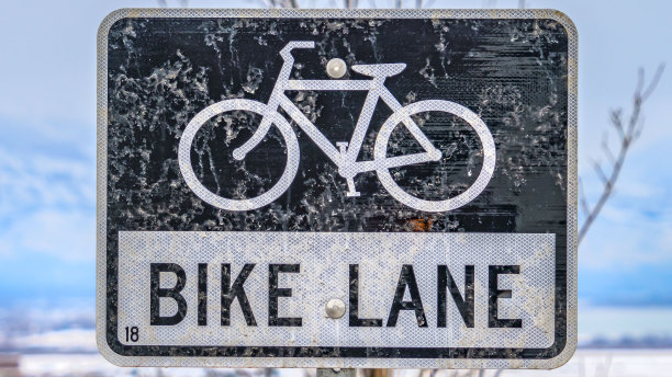 清晰的全景自行车道标志前的树和积雪覆盖的景观在冬天图片下载