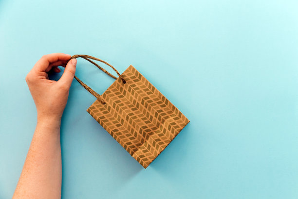 女士手中的礼品和购买工艺包平放在蓝色背景上。回收方案。夏天出售图片下载