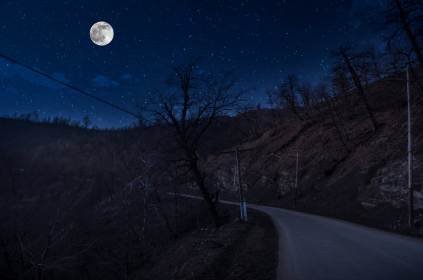 月圆之夜，山路穿过森林。风景优美的夜景乡村小路，夜晚有大月亮。长快门的照片图片下载