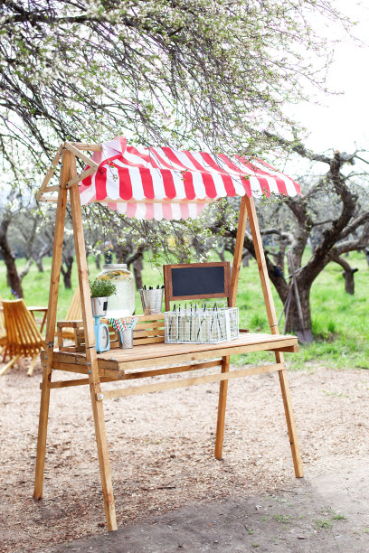 在公园的绿色草坪上有一个放着柠檬水的木制柜台。可爱的夏日柠檬水摊。在花园里自制柠檬水。露天的木架上放着一个玻璃罐里的柠檬水图片下载