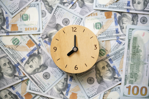 闹钟上一堆美元钞票的背景，赚钱的时间到了。，商业和省钱的概念图片下载