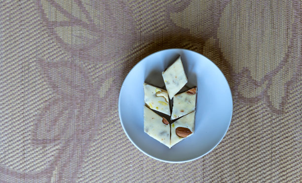 盘子里的东方甜点哈瓦，配开心果、杏仁、腰果、花生、核桃。图片。健康食品。伊朗甜点特写，在Machane Yehuda市场很受欢迎，土耳其软糖。隔离在背景上图片下载