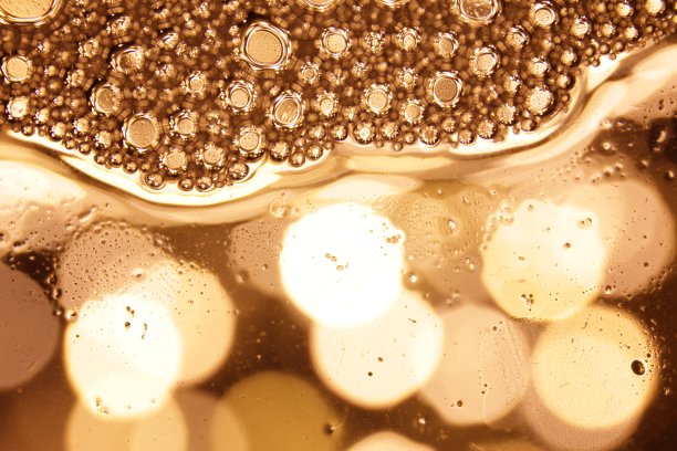 泡沫在水中的黄金背景水平模式。圆形、液体、灯光设计图片下载