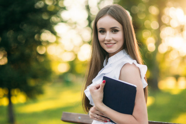 年轻女老师拿着写字板在外面。公园里的现代教师。戴眼镜的女人图片下载