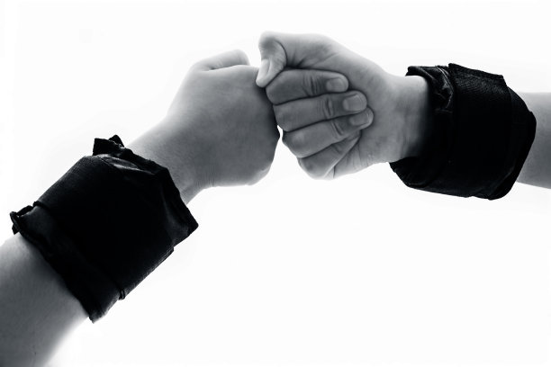 一个男性和另一个女性的手孤立在白色上，戴着黑色的腕带或腕上的砝码孤立在白色上。做各种各样的手势来表现团结和力量。图片下载