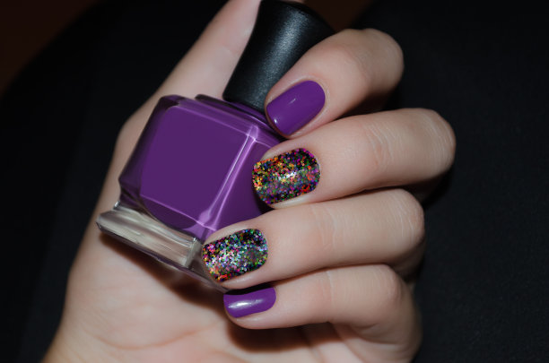 女性手拿紫色指甲设计指甲油瓶图片下载