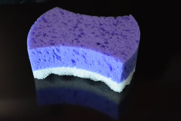 在黑色时尚光泽的背景上是一个女性紫色海绵，紫色和白色的身体反射。图片下载