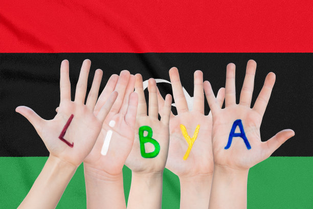 题词利比亚在孩子们的手上，背景是飘扬的利比亚国旗图片下载