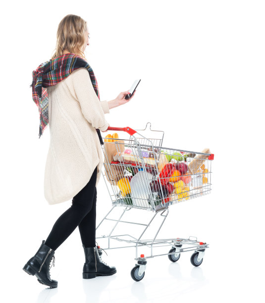 年轻漂亮的女人推着购物车，用手机发短信图片下载