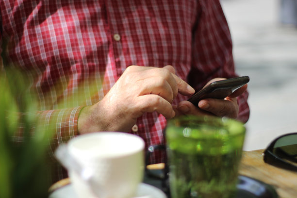 一位在咖啡馆里使用智能手机的老人图片下载