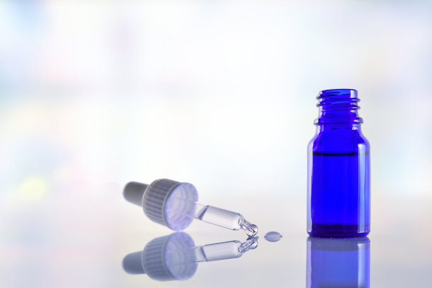 带有滴管的玻璃瓶，白色玻璃桌面，蓝色背景图片下载