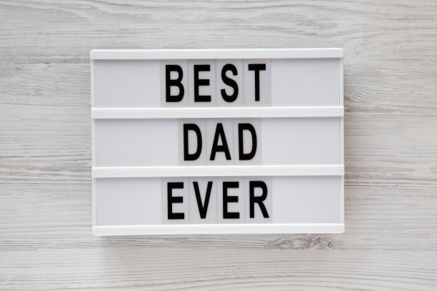“史上最好的爸爸”的字样写在白色木质表面的灯箱上，俯视图。头顶上，从上面看，是平躺着的。图片下载